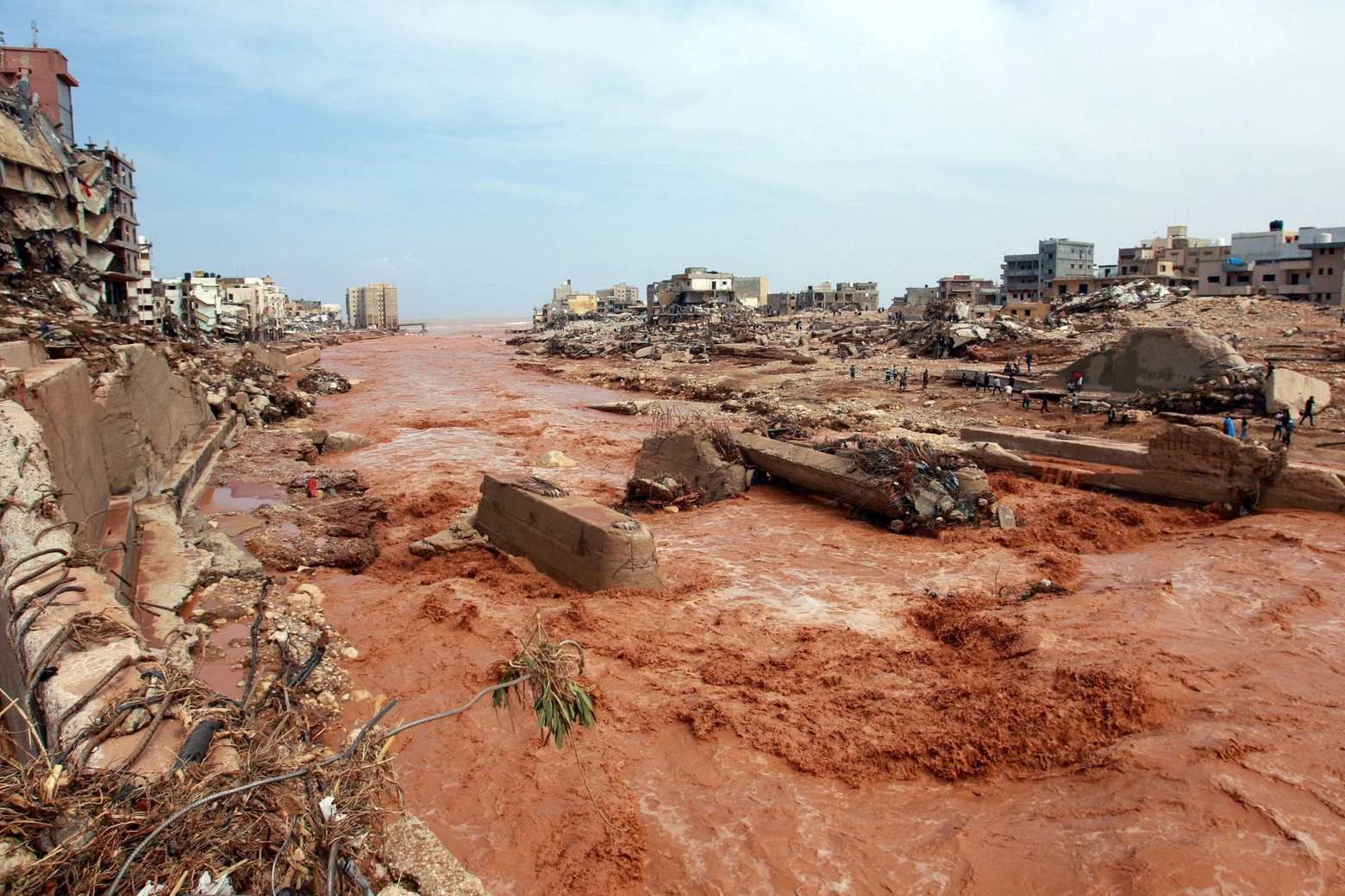 People look at the damage caused by freak floods in Derna, eastern Libya, on September 11, 2023. The death toll from freak floods in eastern Libya is expected to soar dramatically, with 10,000 people reported missing, the Red Cross warned on September 12. Officials in Libya have said at least 150 people were killed in the sudden flooding on Sunday afternoon after storm Daniel swept the Mediterranean, lashing Bulgaria, Greece and Turkey. (Photo by AFP)