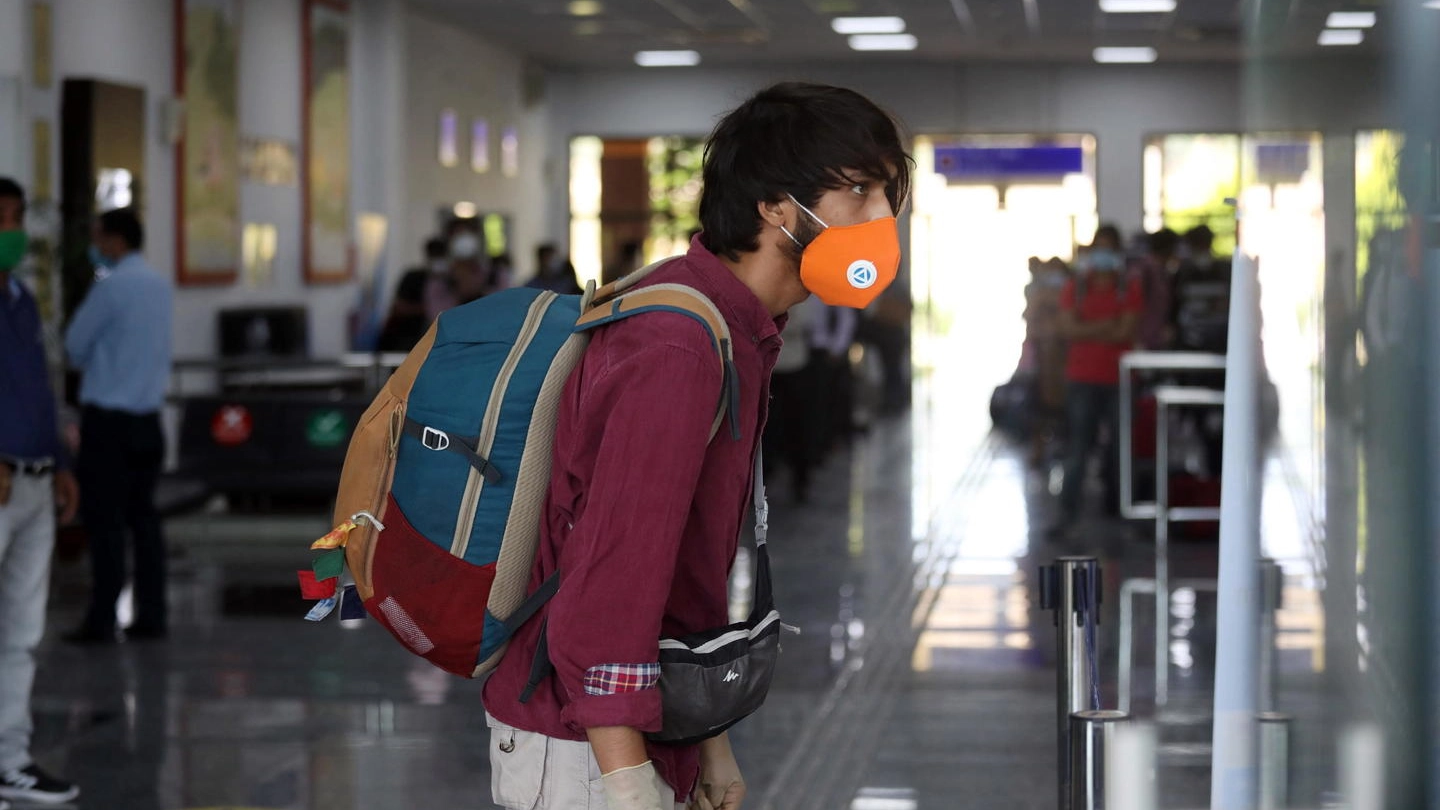 Un viaggiatore con mascherina e guanti in aeroporto (Ansa)