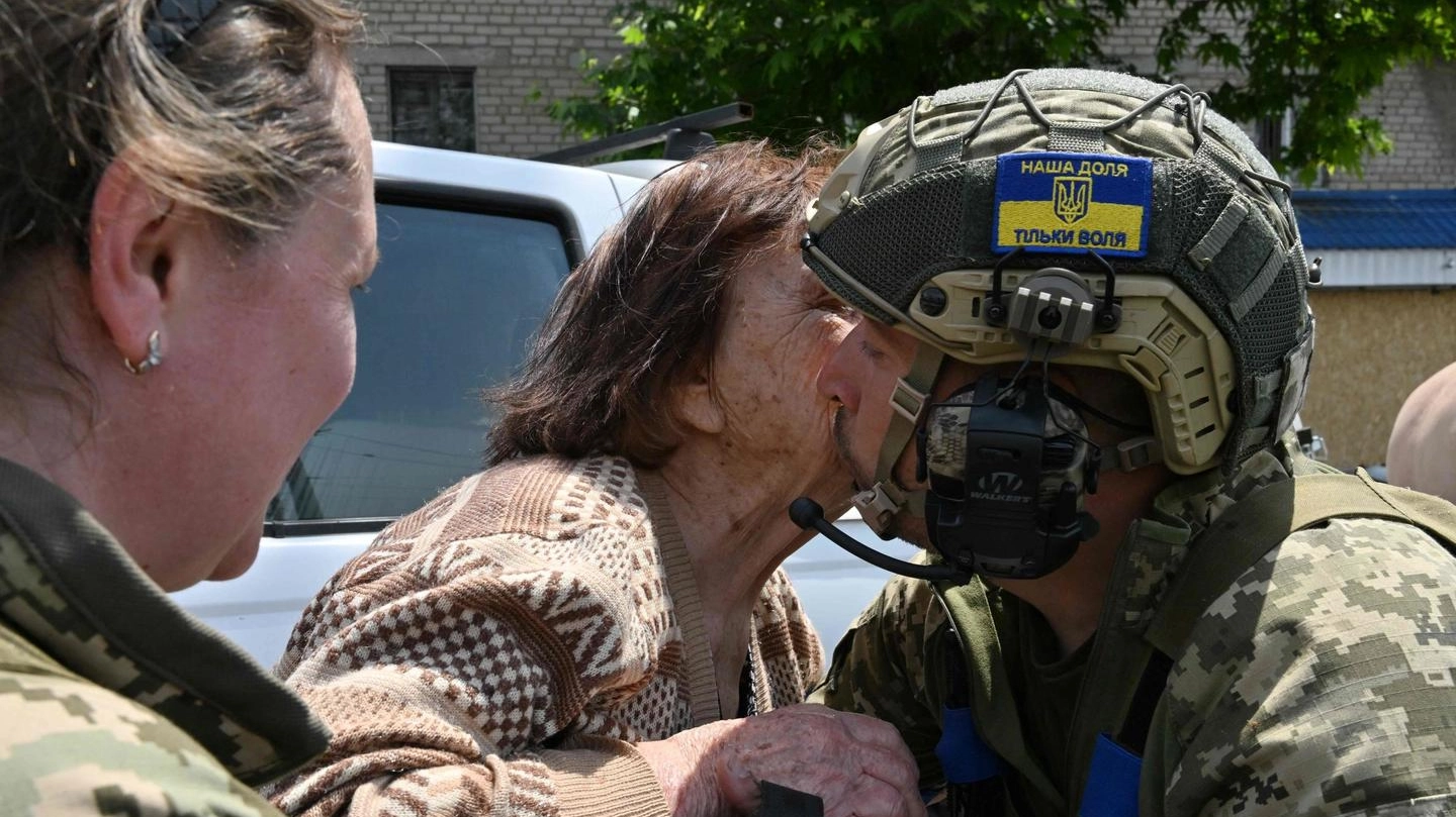 Un’anziana bacia un soldato ucraino dopo l’evacuazione da un’area allagata