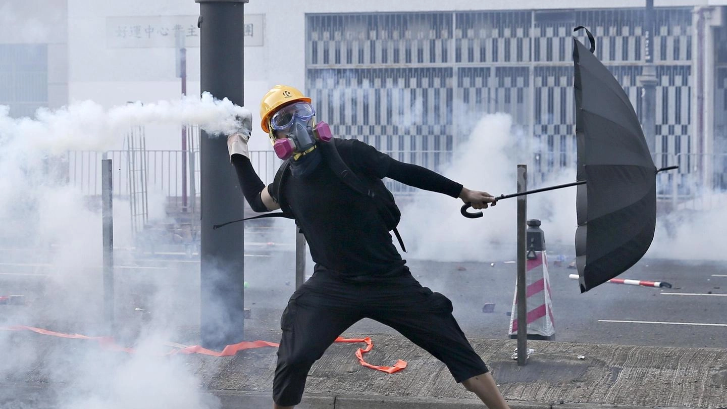 Hong Kong, un manifestante rilancia un gas lacrimogeno verso la polizia (Ansa)
