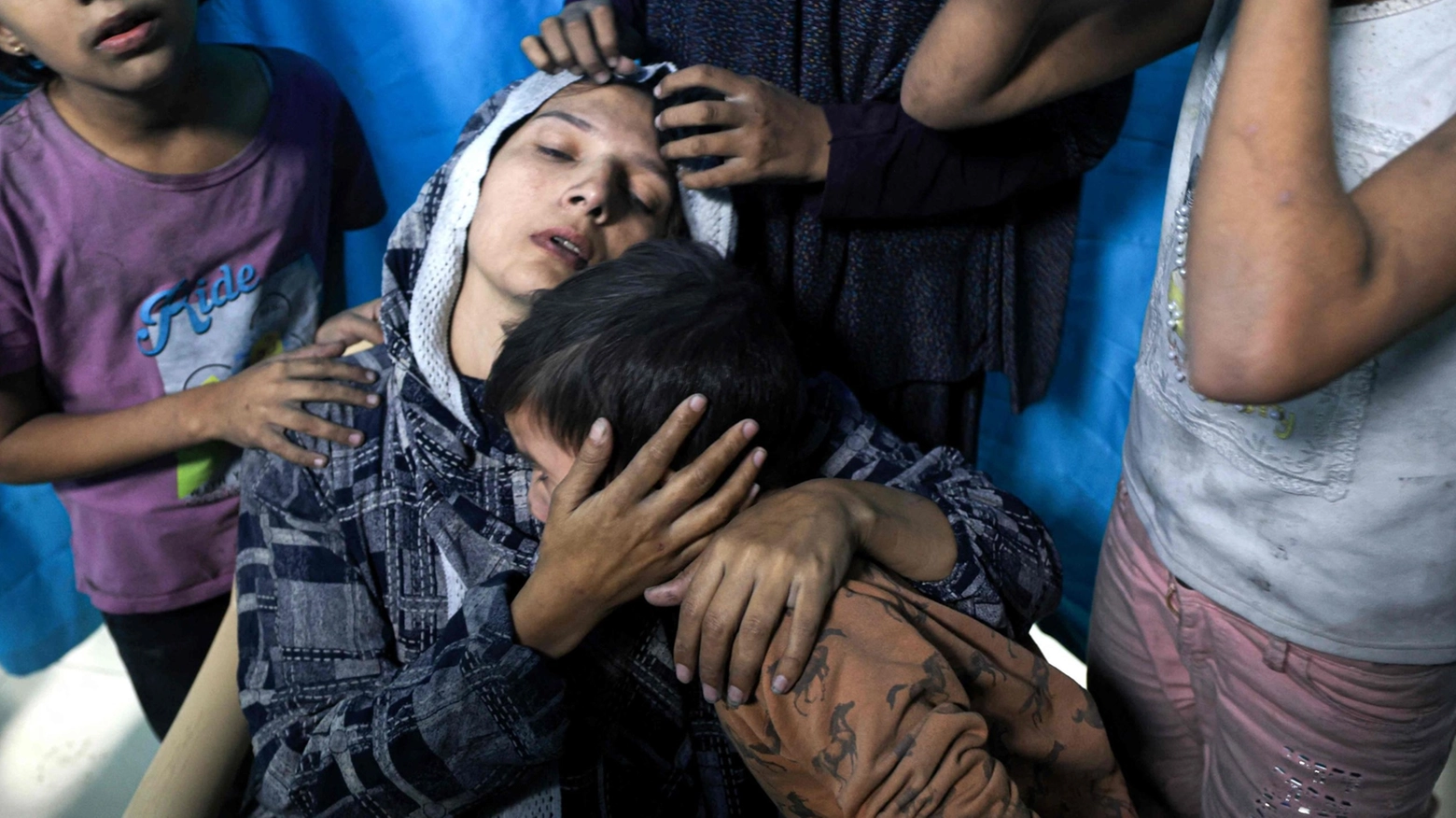 Una donna palestinese ferita circondata dai suoi figli (Ansa)
