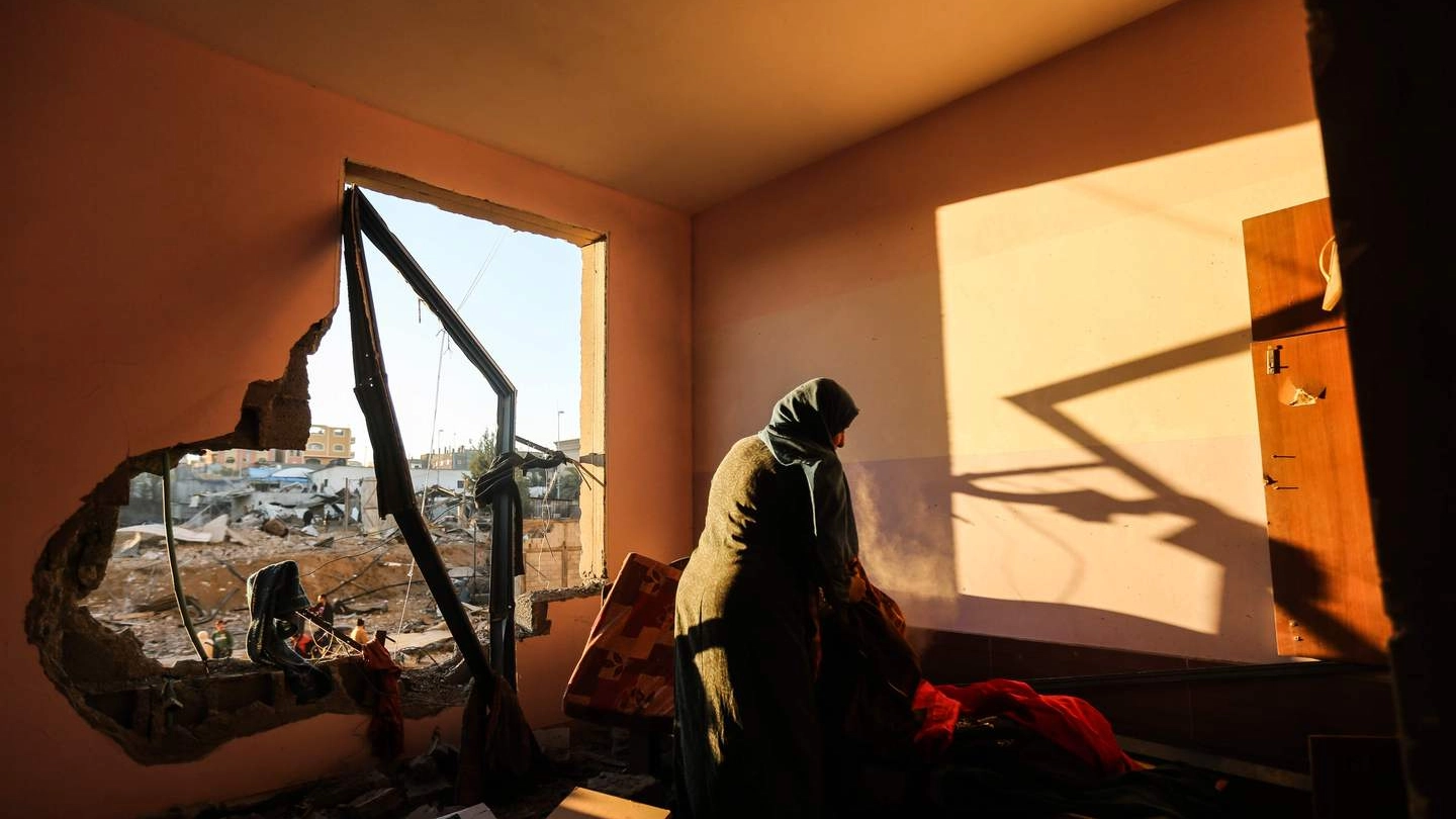 Una donna palestinese nella sua casa distrutta a Gaza (Afp)