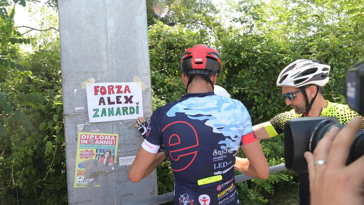 Un gruppo di ciclisti affigge un cartello di supporto per Zanardi (Ansa)