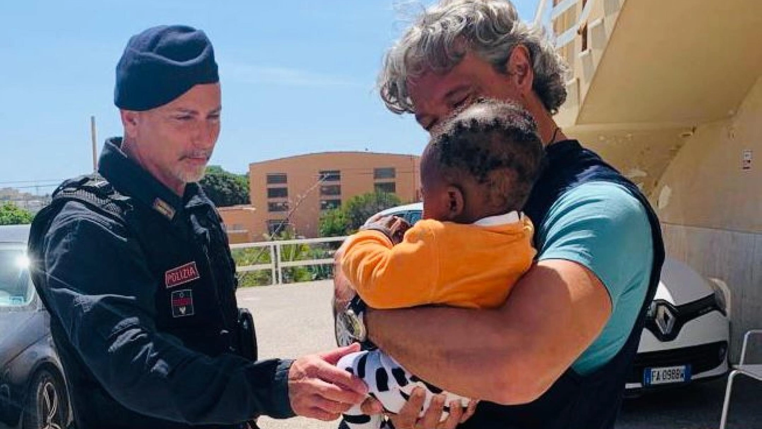 Il piccolo coccolato dai poliziotti a Lampedusa (Ansa)