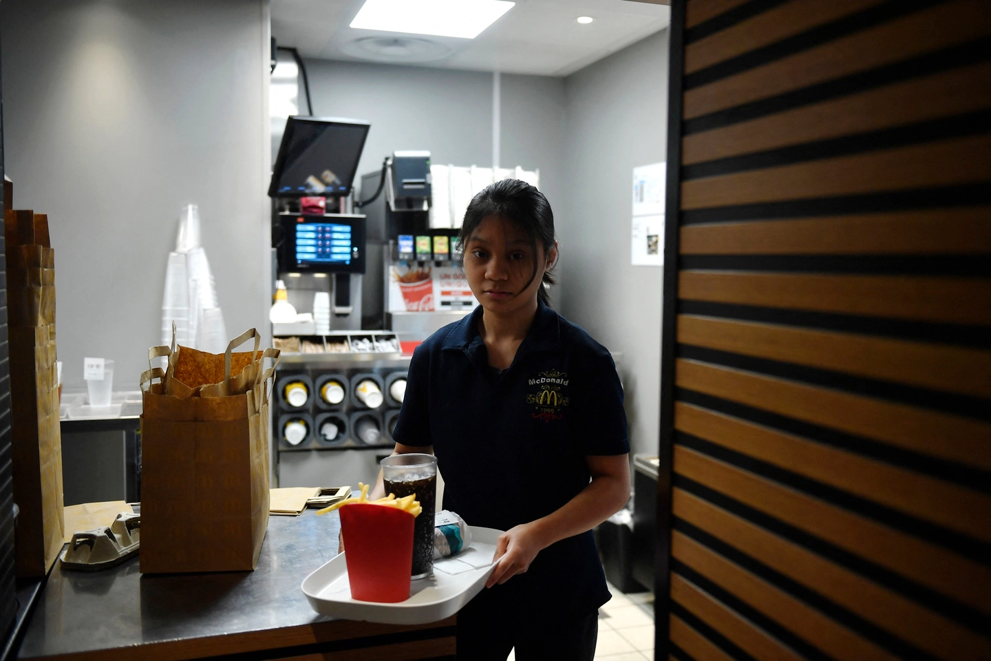 Un'impiegata di McDonald's a Parigi pronta a servire un vassoio con piatti riutilizzabili