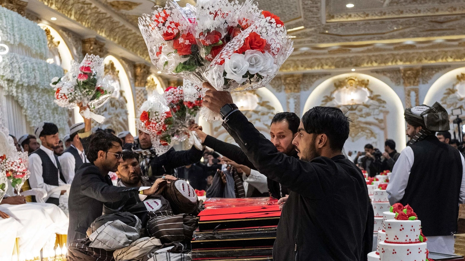 Volontari distribuiscono bouquet di fiori agli sposi per la cerimonia di nozze collettiva a Kabul (Ansa)