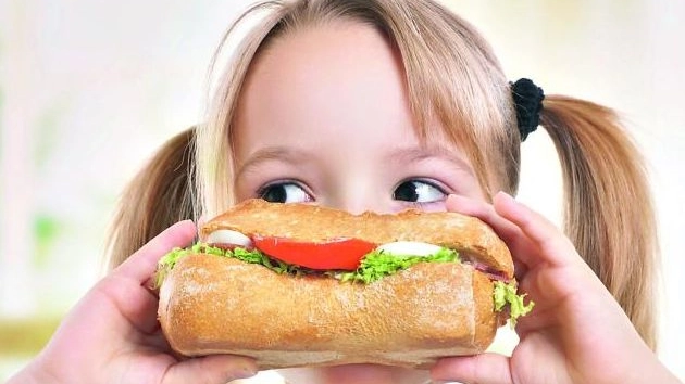 Una bimba mangia un panino, foto generica