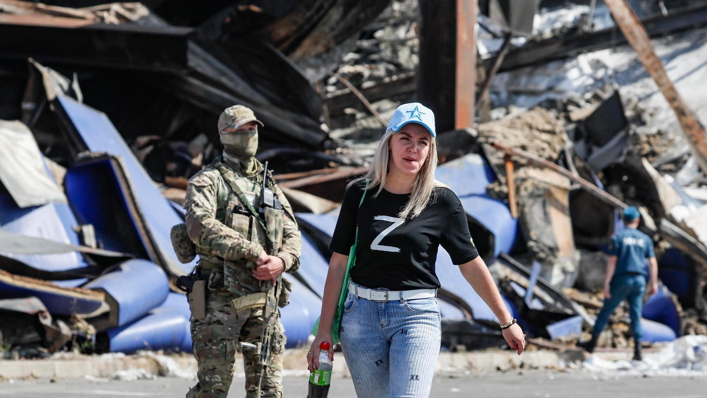 Un soldato russo grada una ragazza a Donetsk (Ansa)