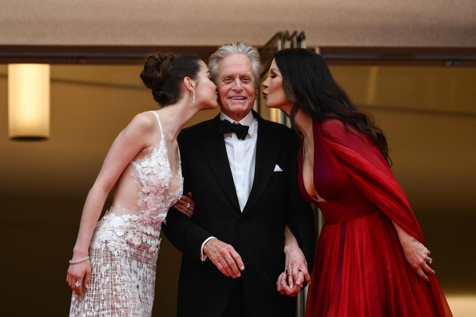 British actress Catherine Zeta-Jones (R) and her daughter Carys kiss US actor and Honorary Palme d’or of the 76th Festival de Cannes Michael Douglas as they arrive for the opening ceremony and the screening of the film "Jeanne du Barry" during the 76th edition of the Cannes Film Festival in Cannes, southern France, on May 16, 2023. (Photo by CHRISTOPHE SIMON / AFP)