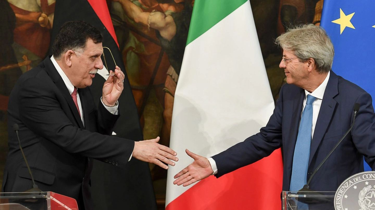 Stretta di mano tra il premier libico al-Serraj e quello italiano Gentiloni (Afp)