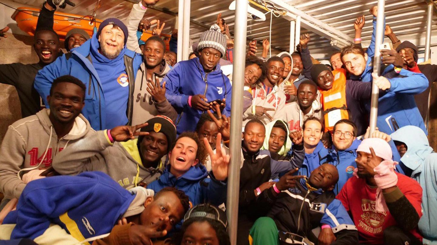 I migranti sulla nave Jonio festeggiano prima di sbarcare al molo di Lampedusa (Ansa)