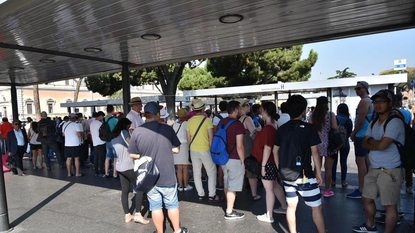 Persone in attesa alla fermata di un autobus durante lo sciopero dei mezzi a Roma (Ansa)