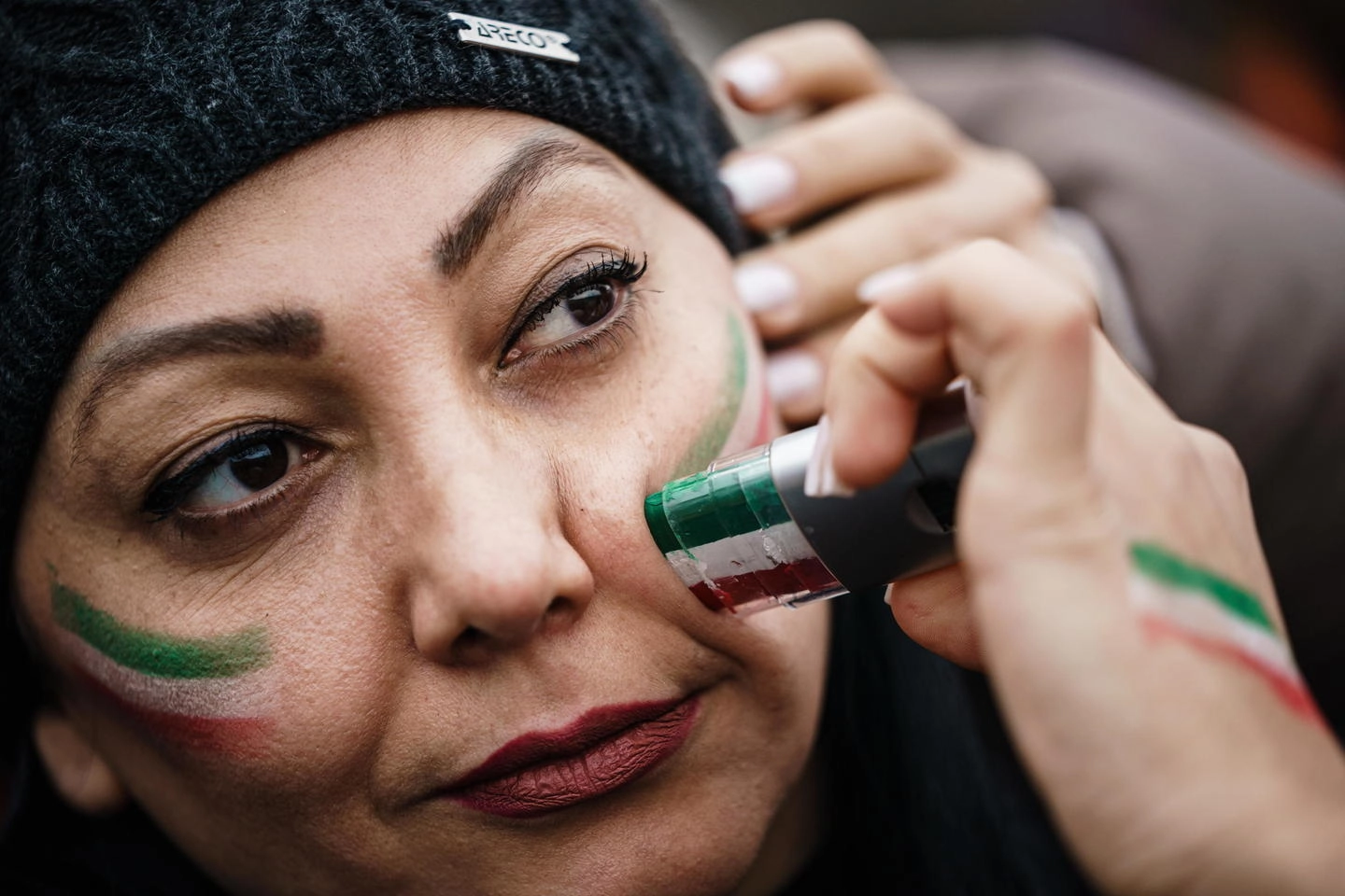 Una donna che protesta con la bandiera iraniana dipinta in volto