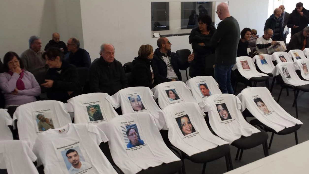 Le t-shirt con le foto delle 32 vittime sono lì a ricordare a tutti che il processo riguarda la morte di 32 persone innocenti
