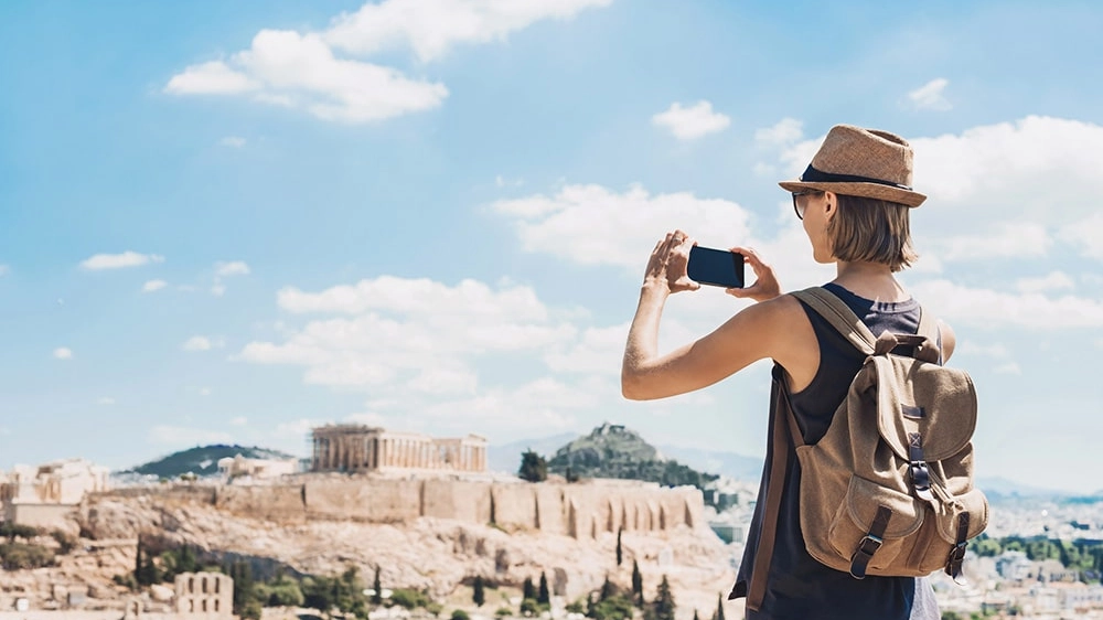 Woman taking photos with smartphone on vacations in Athens