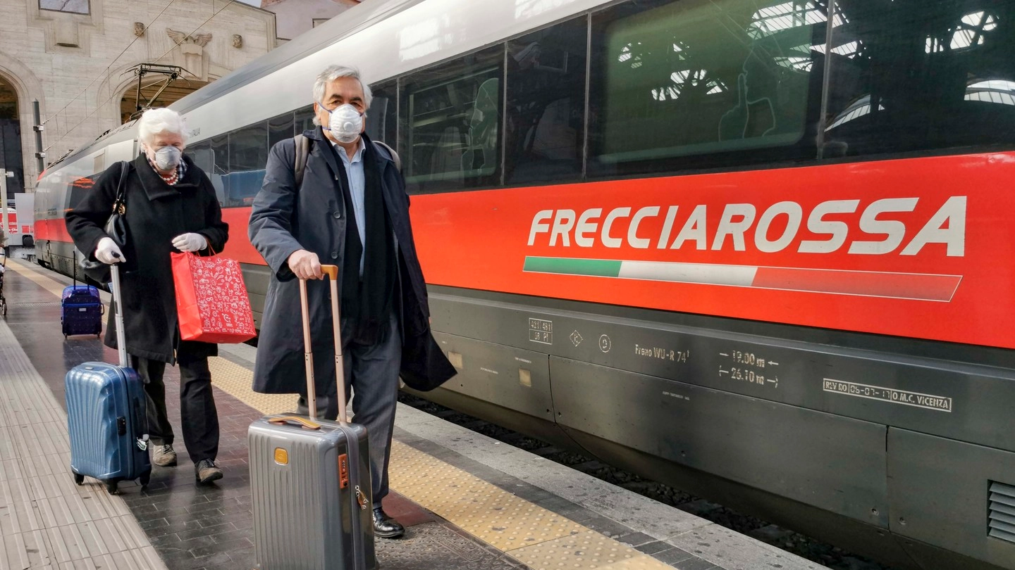 Stazione Centrale di Milano, due passeggeri con la mascherina (Ansa)