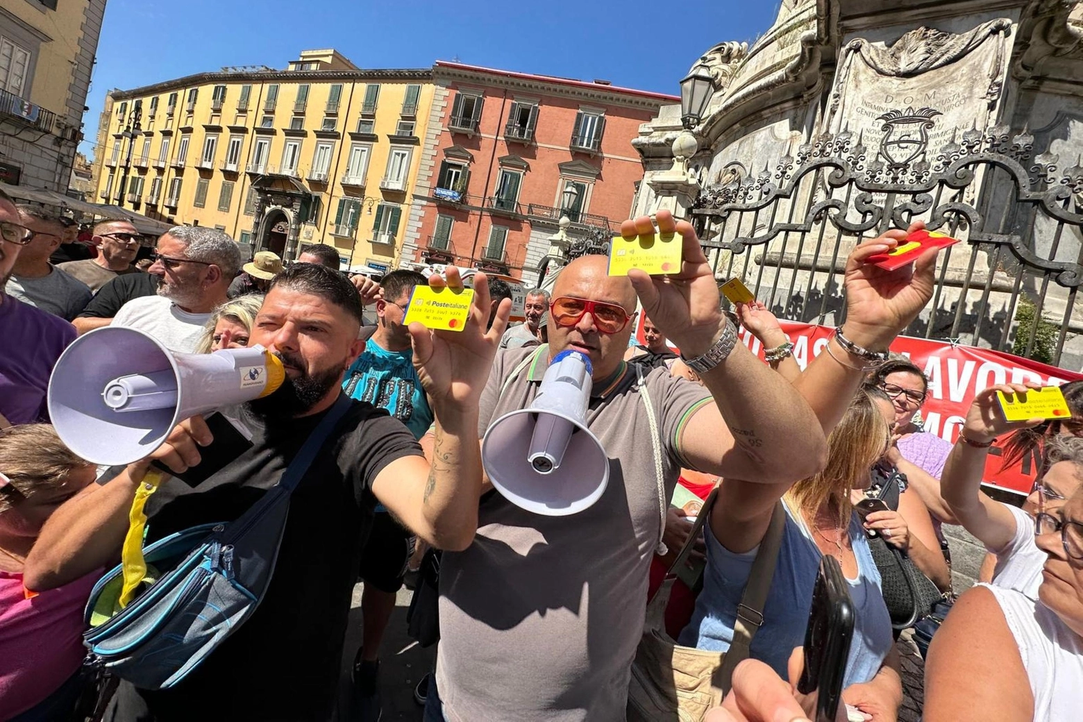 I manifestanti mostrano la card gialla del reddito di cittadinanza durante la protesta a Napoli