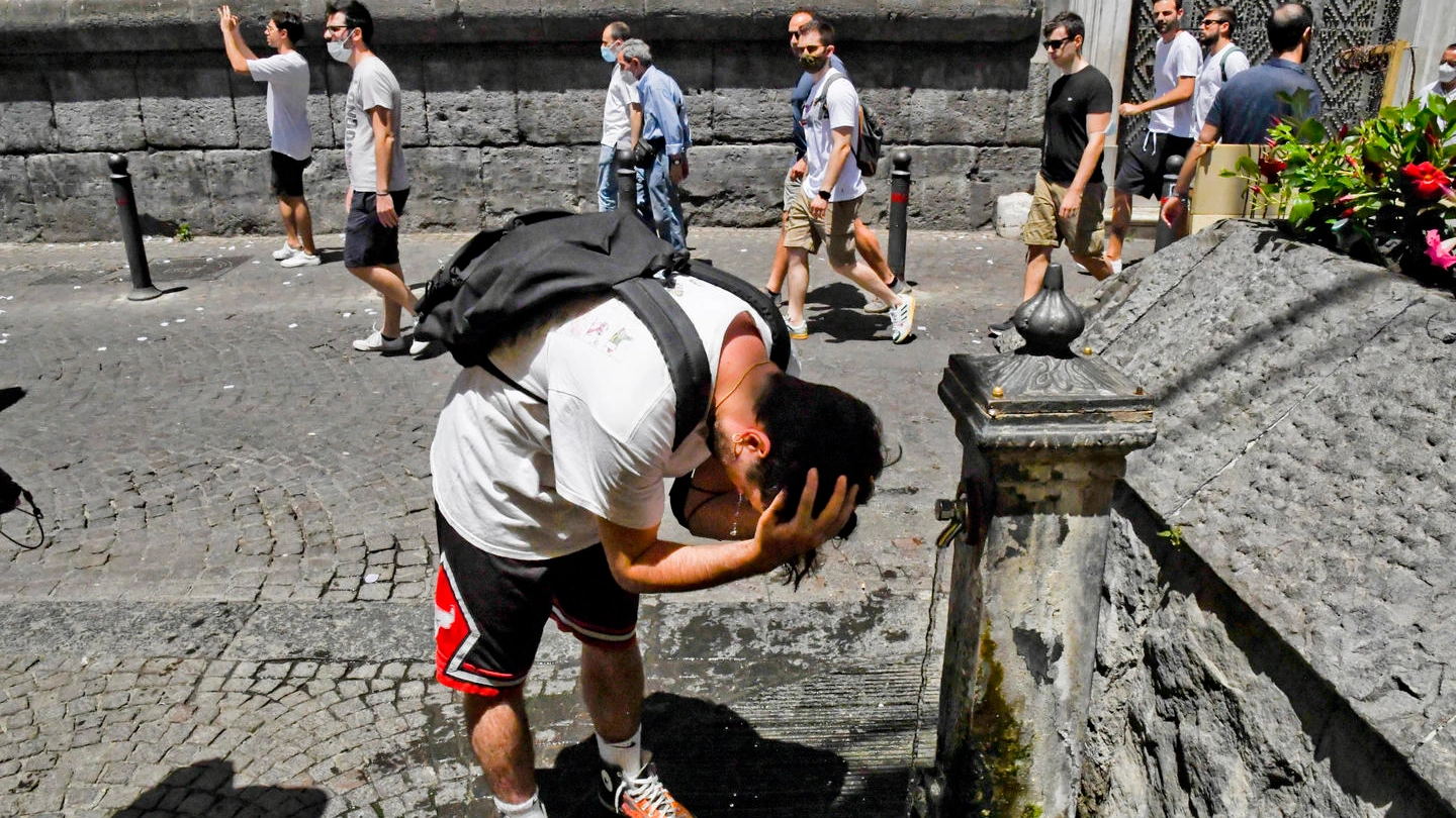 Una persona si difende dal forte caldo bagnandosi ad una fontana  a Napoli (Ansa)
