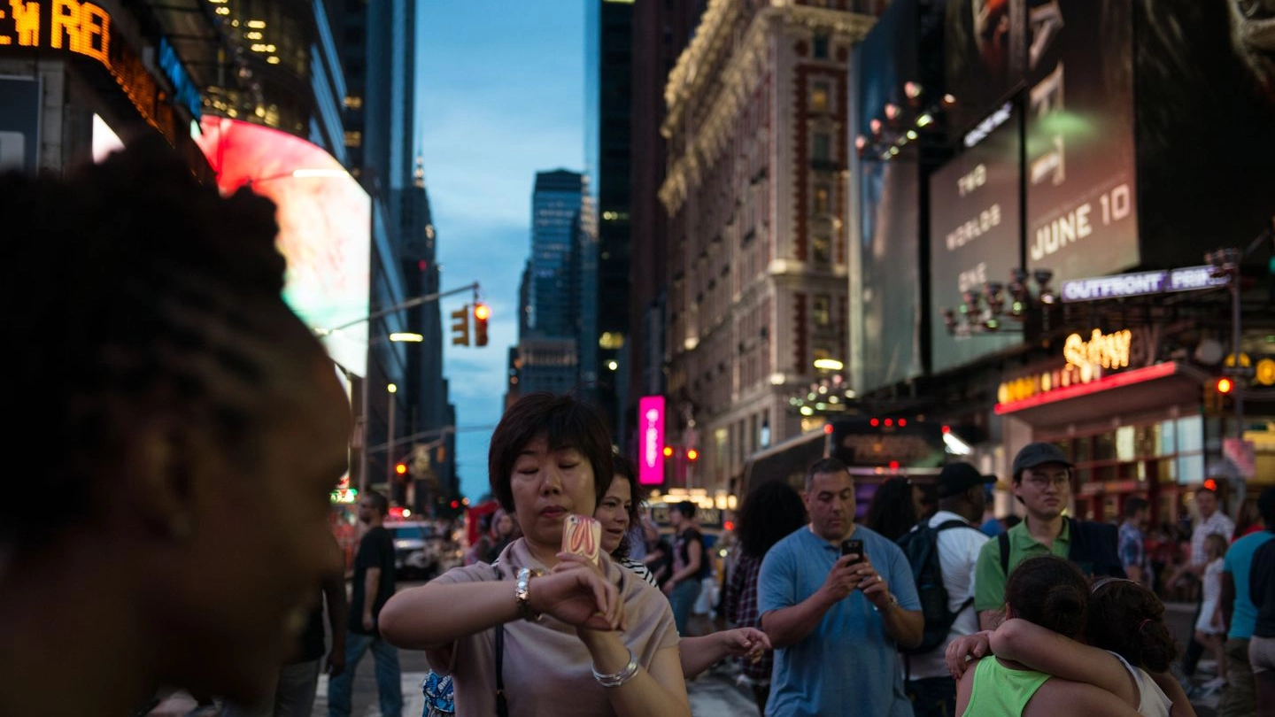 Una donna attende di fare un selfie col Manhattanhenge, ma le nuvole lo impediranno (Afp)