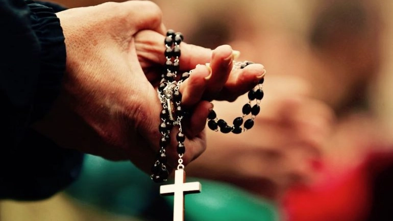 Il rosario tra le mani di un religioso in preghiera