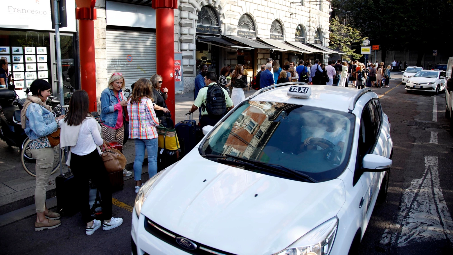 Persone in fila per prendere un taxi a Milano (Ansa)