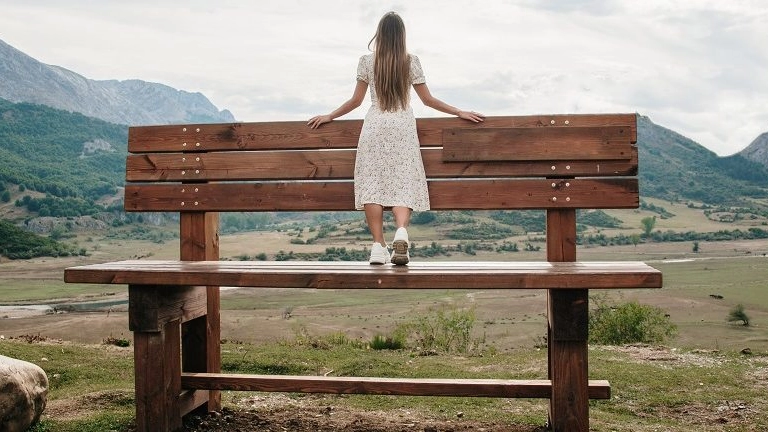 Young woman on a giant bench in a mountain area