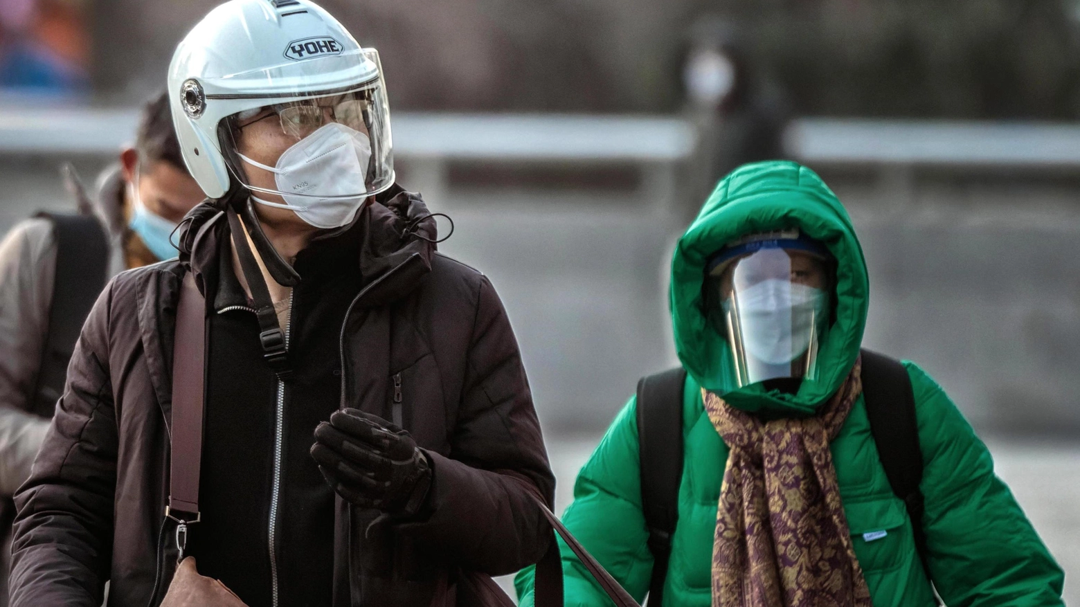 Due cittadini cinesi con i volti coperti da caschi, cappucci, mascherine e visiere