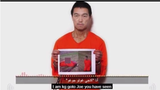 Il fermo immagine tratto dal video con Kenji Goto che ha in mano una foto di Yukawa decapitato