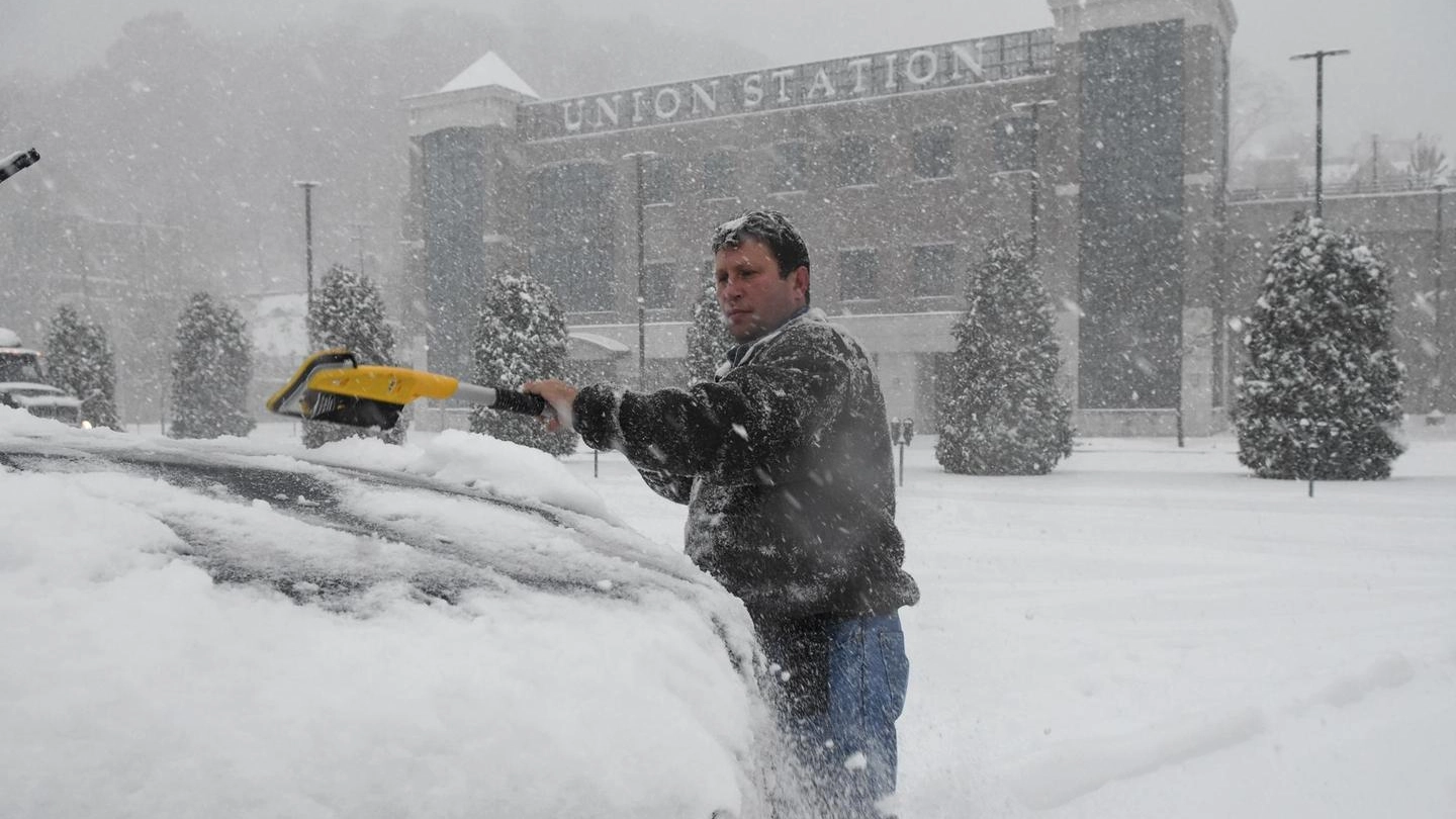 Un uomo impegnato a liberate la sua auto dalla neve (Ansa)