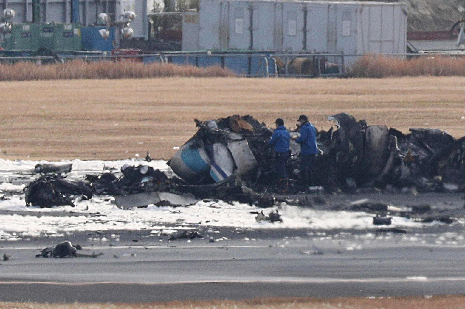 Tokyo, i resti dell'Airbus bruciato sulla pista di Haneda (Ansa)