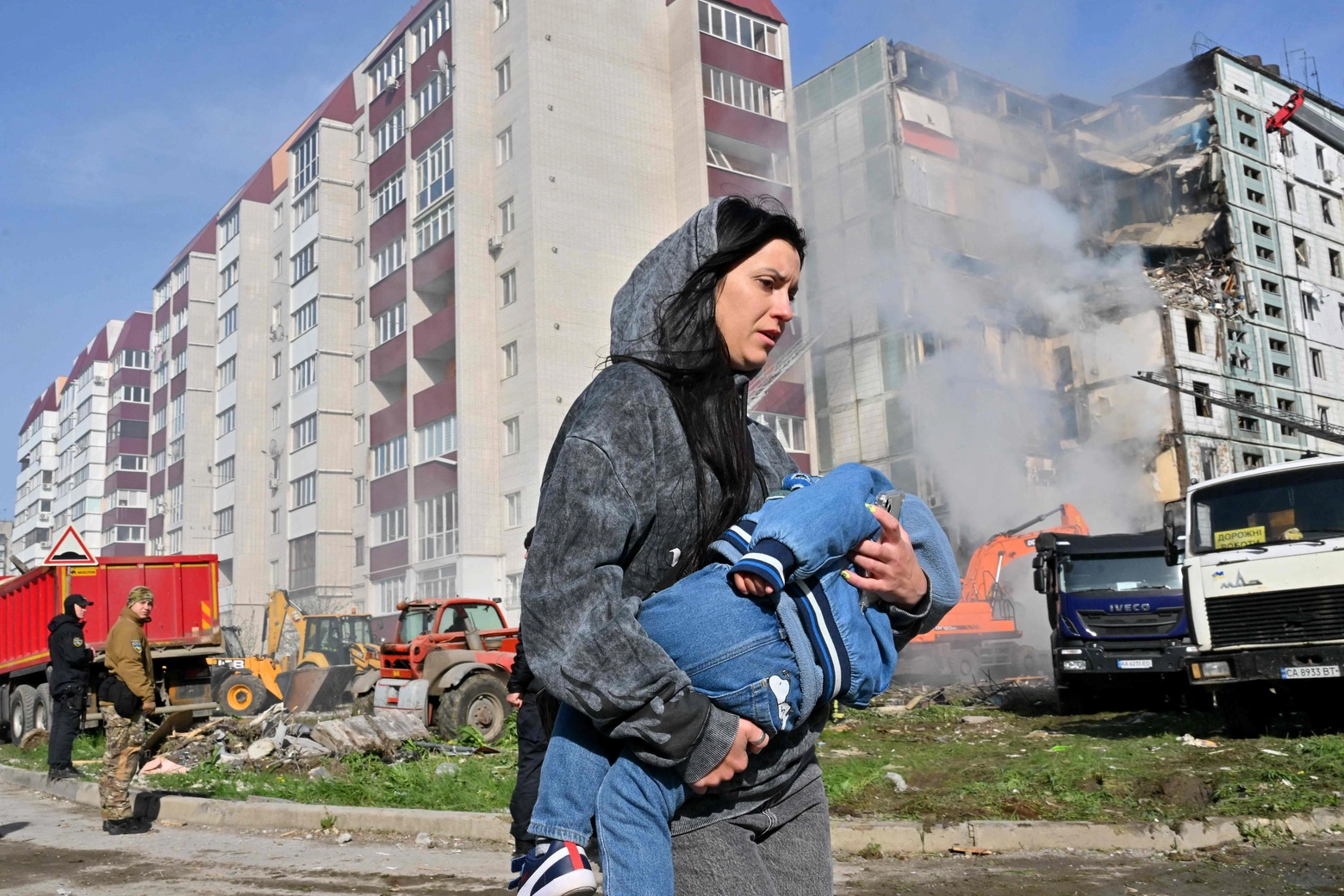 Un donna con in braccio un bambino davanti al condominio bombardato a Uman (Afp)