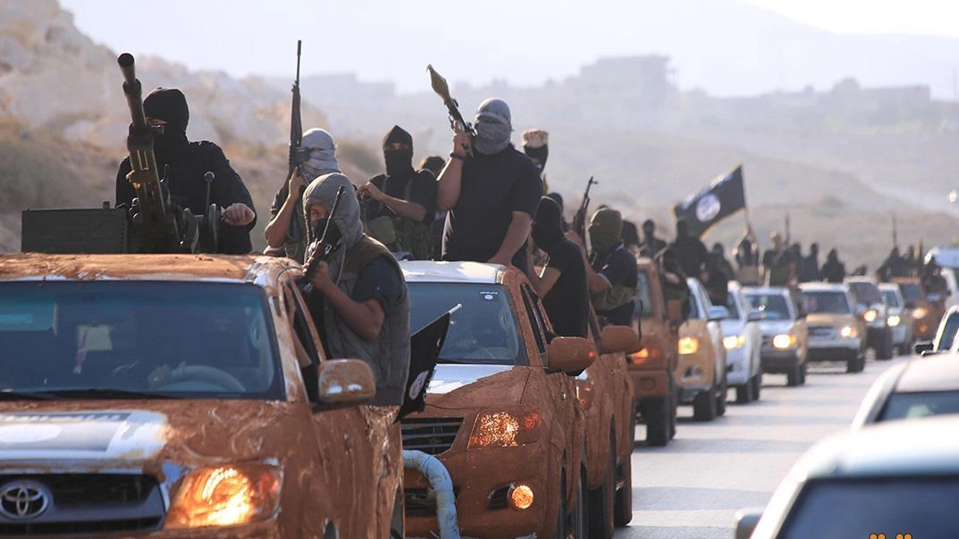 Un convoglio di pickup con a bordo uomini armati e bandiere nere dell'Isis (Ansa)