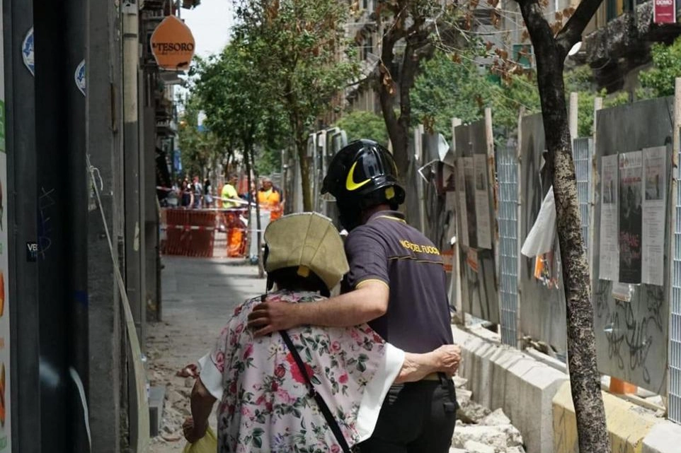 Vigili del fuoco scortano i passanti in centro a Napoli (Ansa)