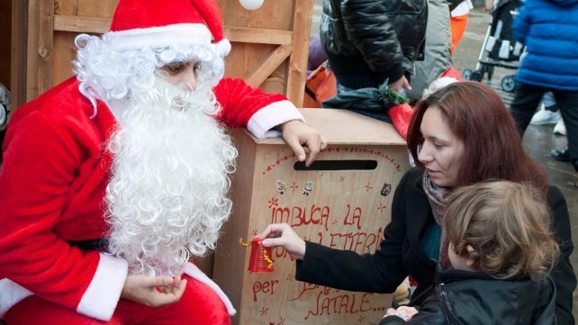 Un bambino  dà la sua letterina  a Babbo Natale  in un centro commerciale