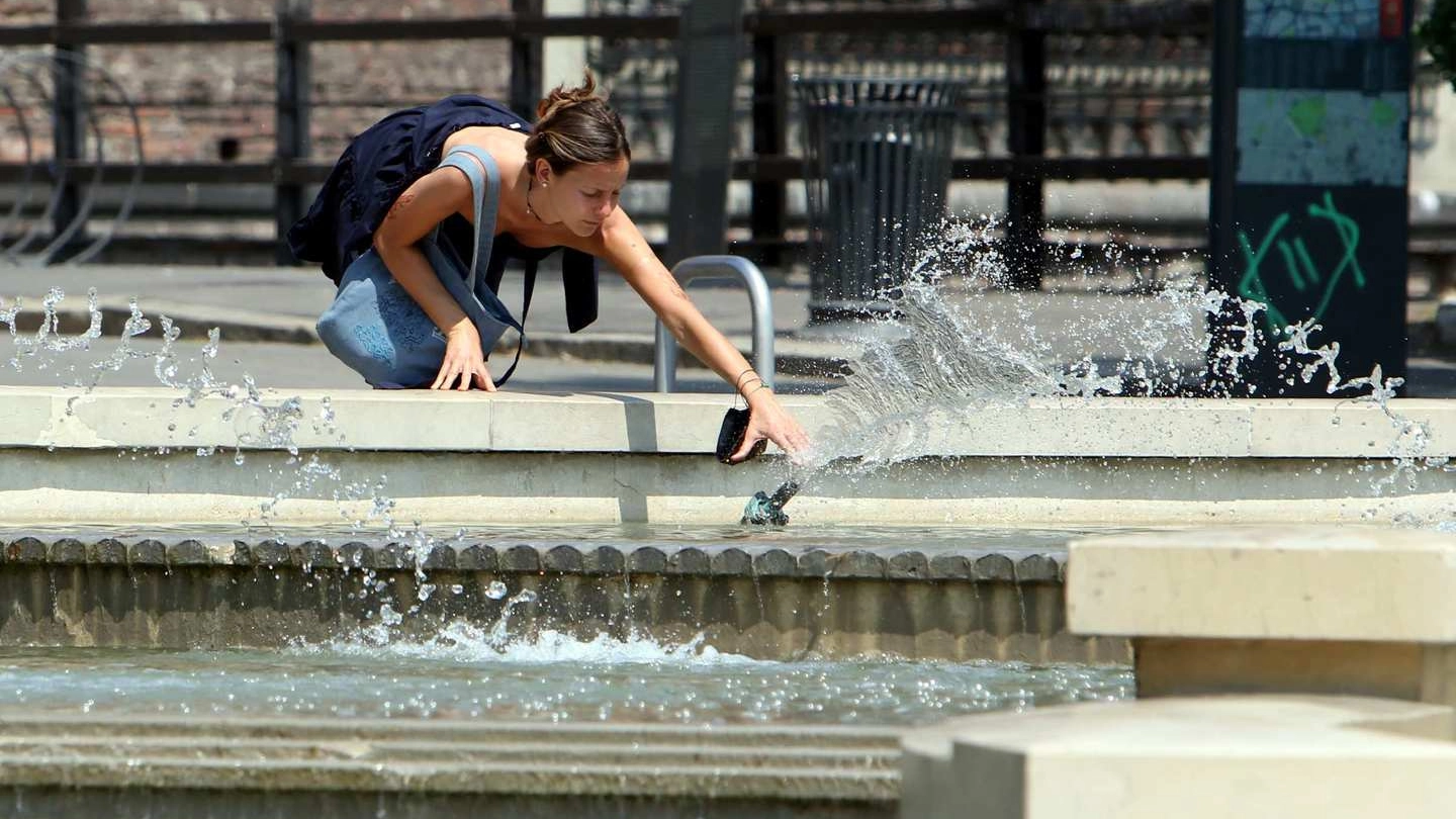 Milano, una ragazza si rinfresca in una fontana (Ansa)