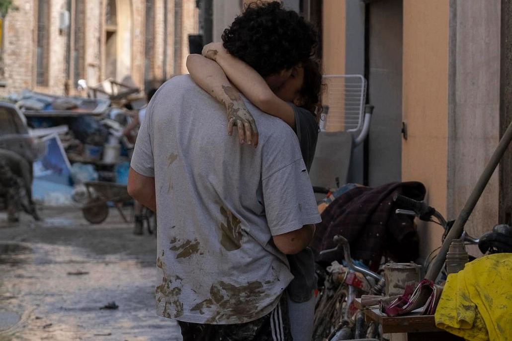 Una giovane coppia si bacia in mezzo ai detriti a Faenza (Ravenna)