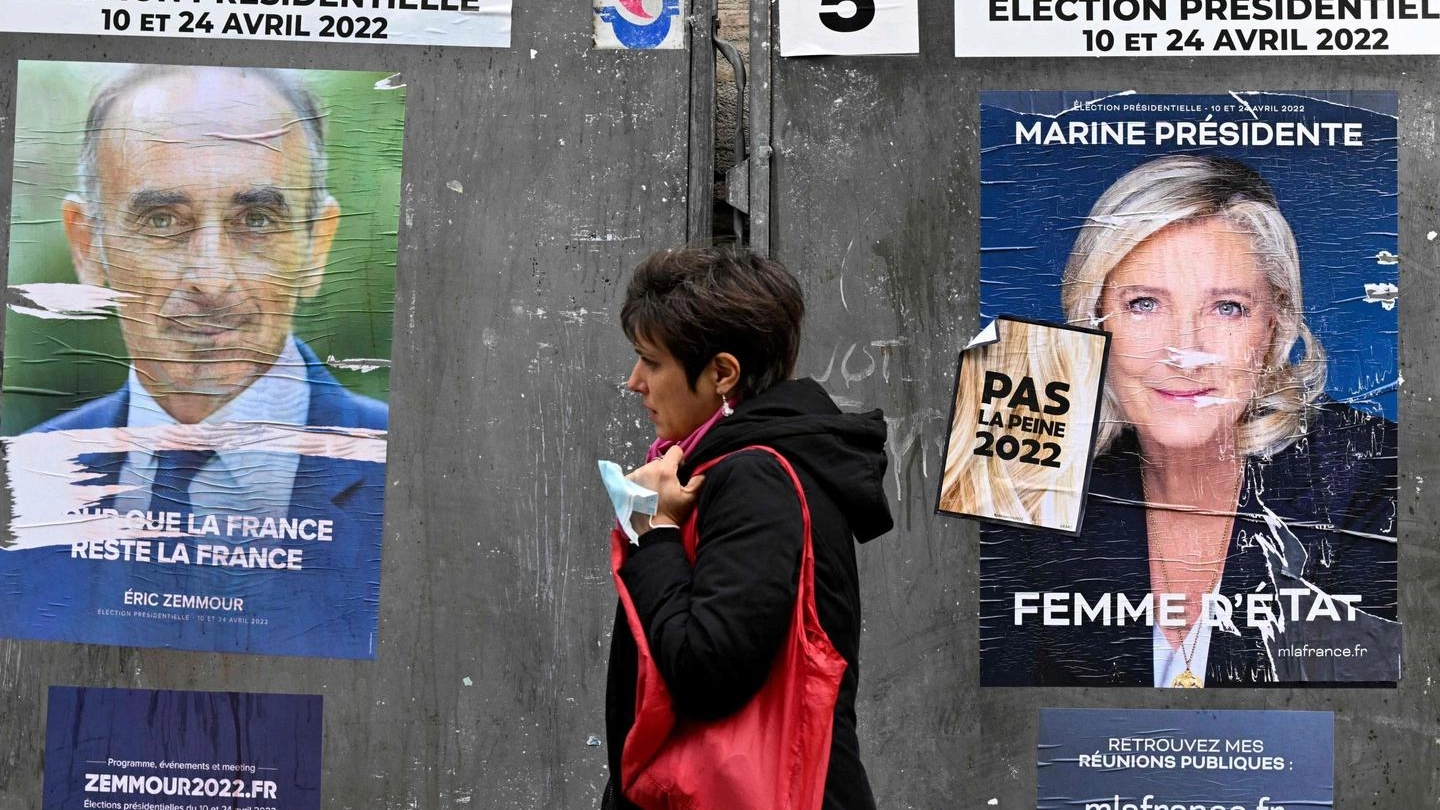 Parigi, una donna passa davanti ai manifesti di Éric Zemmour e Marine Le Pen