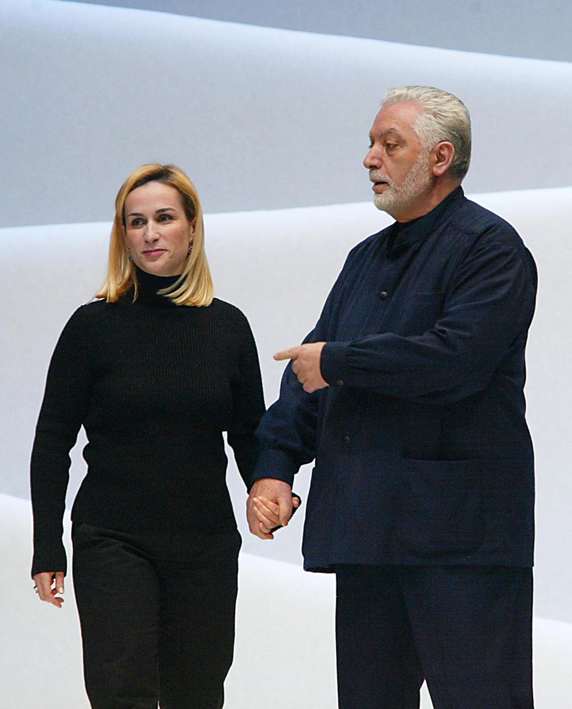 (FILES) In this file photo taken on March 11, 2002, Spanish designer Paco Rabanne (R) acknowledges the audience and his design partner Rosemary Rodriguez (L) in Paris during the Autumn-Winter 2002/2003 ready-to-wear collections. - Spanish fashion designer Paco Rabanne, known for his eccentric clothing designs and for founding one of the world's best-known fragrance brands, died on Friday at the age of 88. Rabanne's death was confirmed to AFP by the parent company of his brand, who said he had "marked generations with his radical vision of fashion and his legacy will live on." (Photo by JEAN-PIERRE MULLER / AFP)