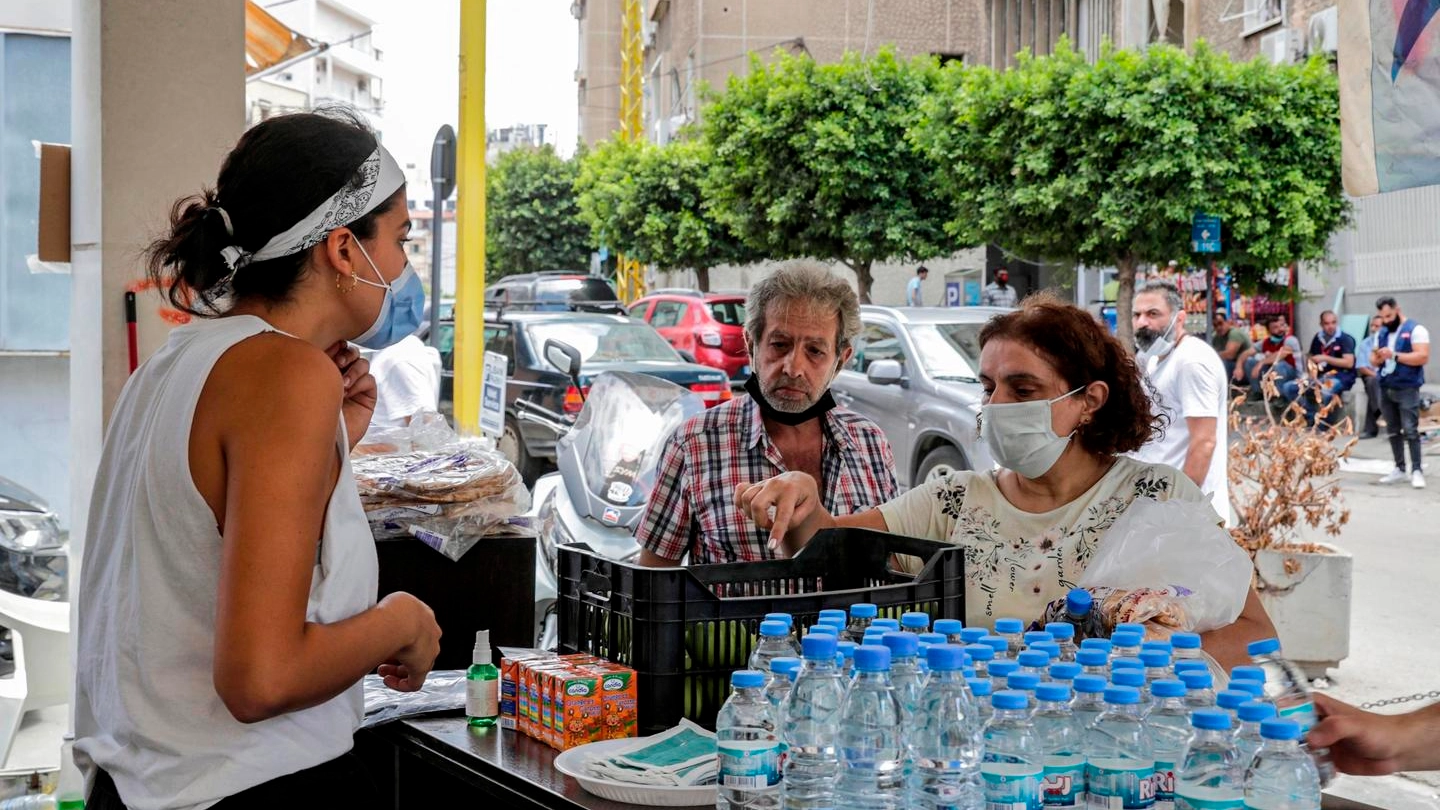 Libano, volontari in maschera distribuiscono cibo e acqua (Ansa)