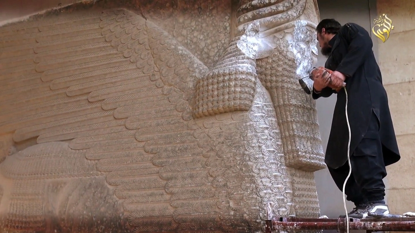 Un estremista dell'Isis distrugge una statua della civiltà assira (Afp)
