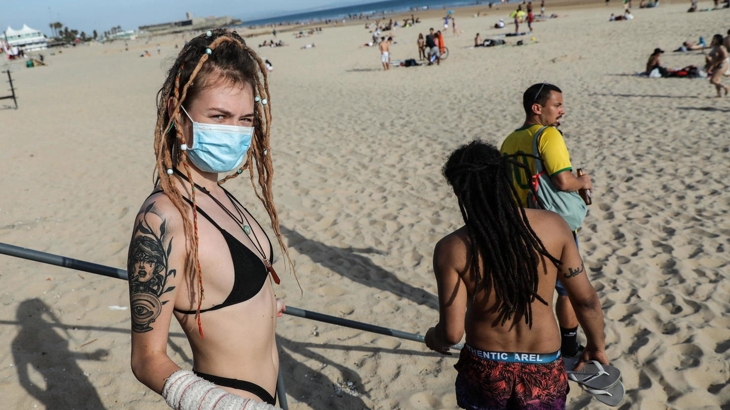 Una ragazza in spiaggia con la mascherina (Ansa)