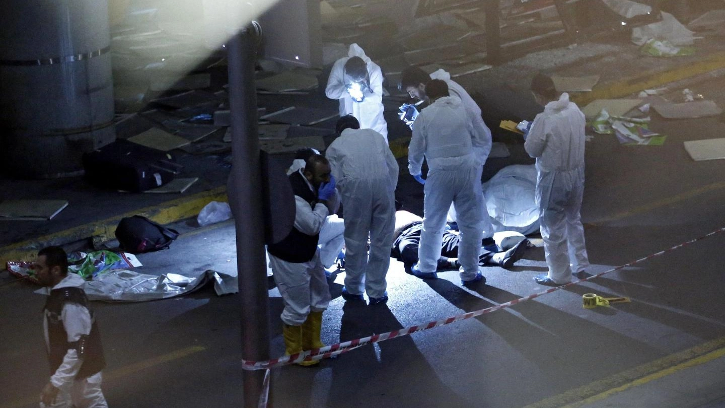 La scientifica fotografa i corpi delle vittime fuori dall'aeroporto (Ansa)