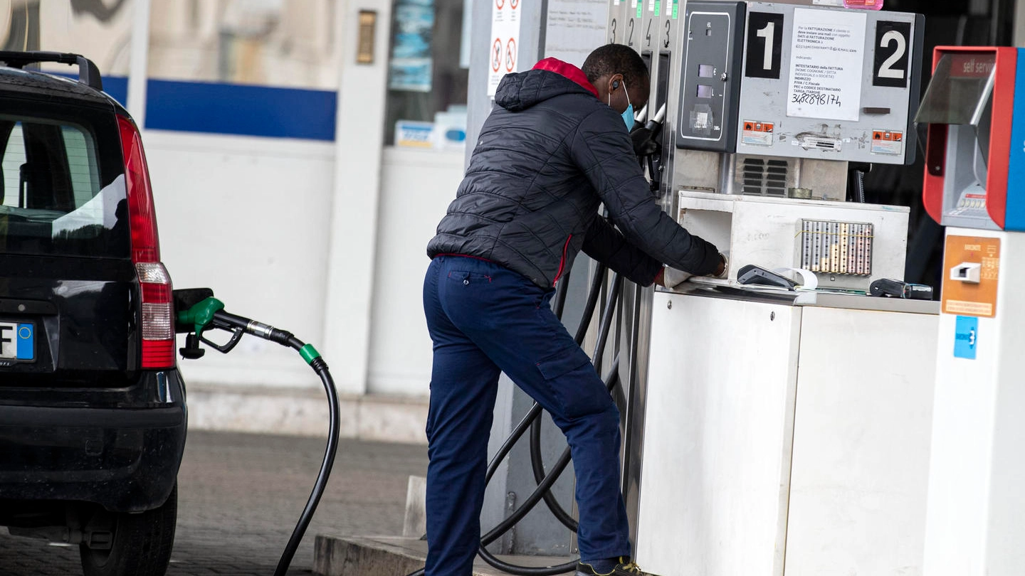 Una persona fa rifornimento a un distributore di benzina (Ansa)