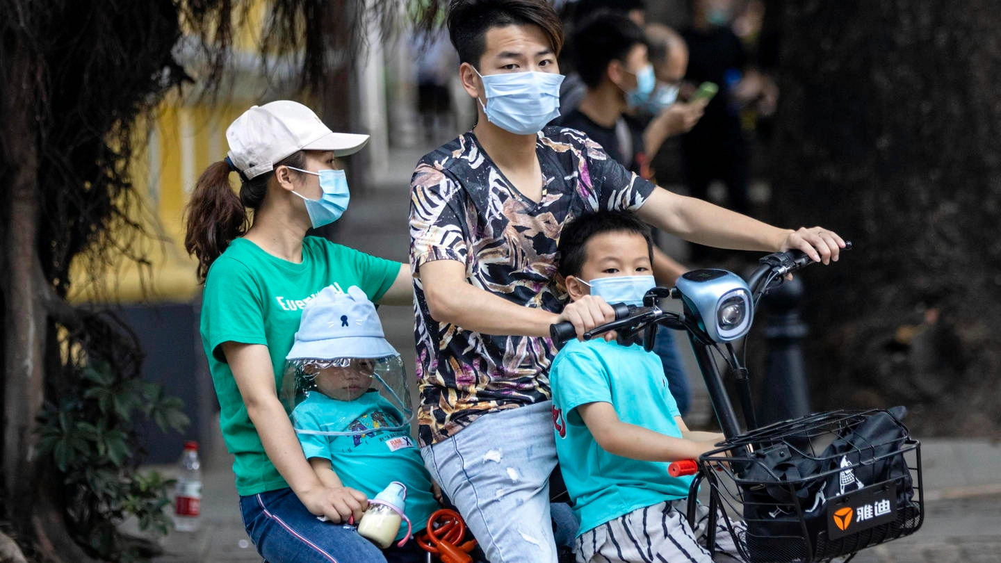Una famiglia cinese in scooter: mascherina anche ai bambini (Ansa)