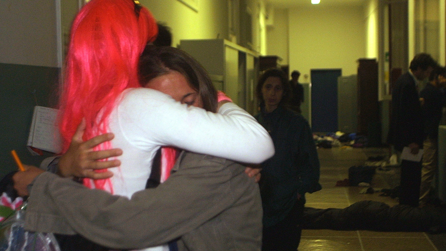 Due ragazze si abbracciano piangendo in un corridoio della scuola Diaz (Ansa)
