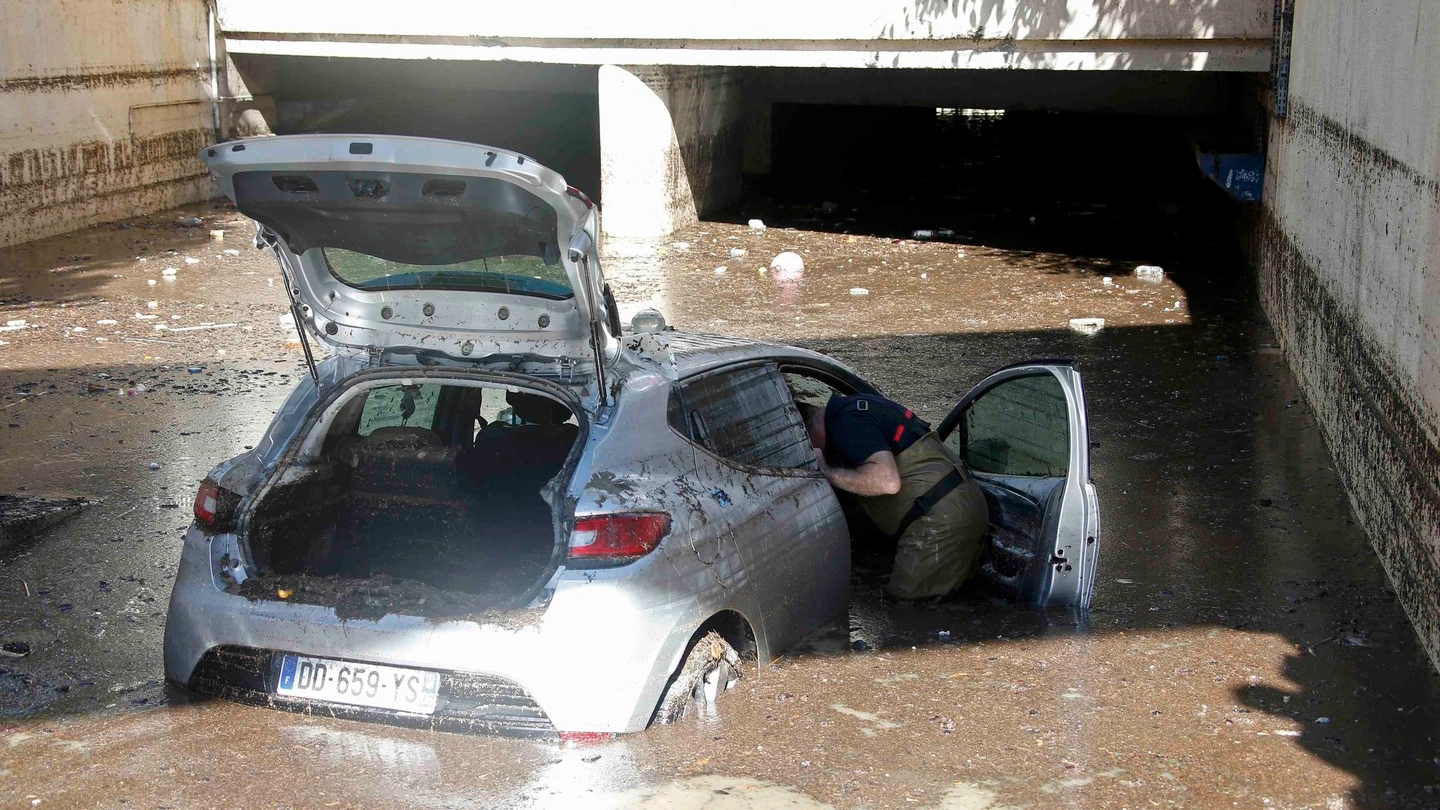 Un vigile controlla un'auto travolta durante l'alluvione in Costa Azzurra (Lapresse)