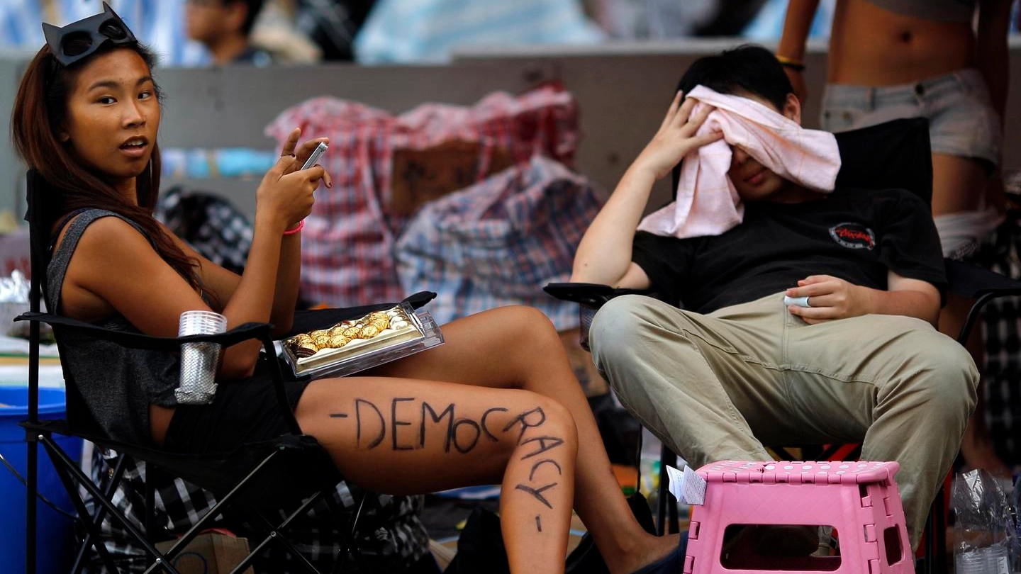 DECISI Una manifestante si riposa sotto una tenda, mentre presidia un’area di fronte al quartier generale del governo di Hong Kong. Sotto, un attivista con lo scudo di Capitan America. In alto, la polizia porta via uno studente (Reuters)