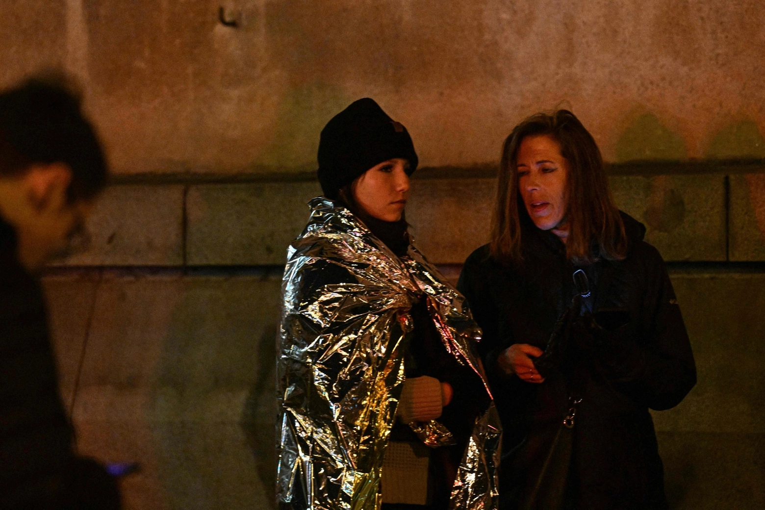 Una ragazza con la coperta termica fuori dall'università di Praga (Ansa)