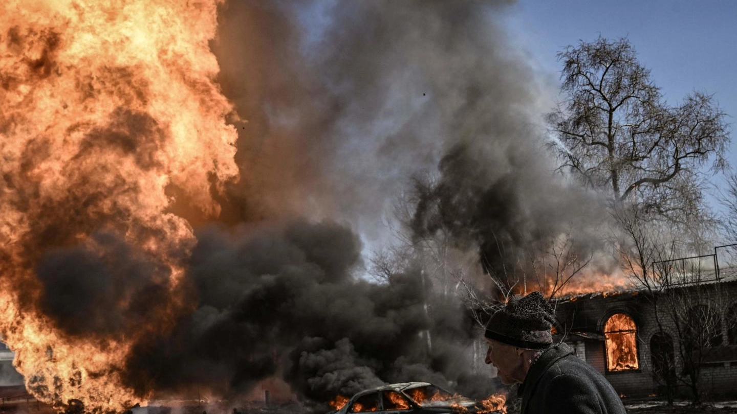 Una donna cammina tra le fiamme a Kharkiv (Ansa)