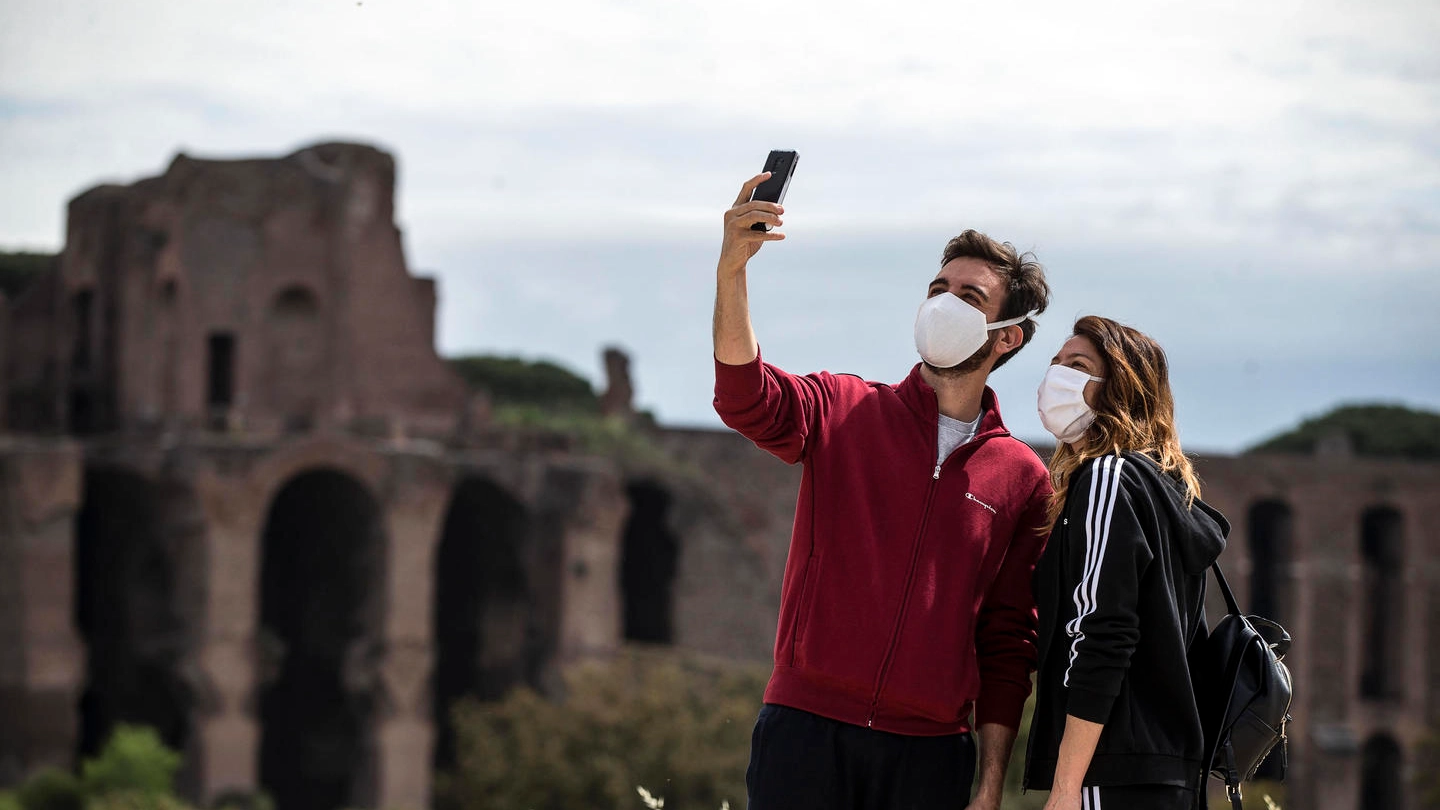 Roma, una coppia posa per un selfie in mascherina (Ansa) davanti al Circo Massimo